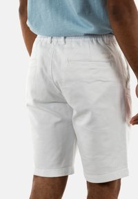 Witte katoenen shorts met een elastische tailleband, achterzakken met flappen en een nette, rechte snit. Glad textuur.