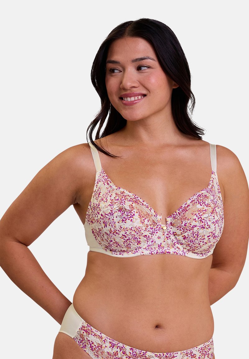 Bralette en dentelle florale crème avec des motifs roses, violets et verts ; dispose de bretelles réglables et d'un détail de bouton décoratif central.