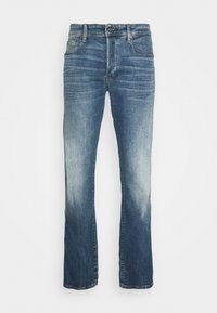 Jeans in denim blu scuro con taglio dritto, caratterizzati da un lavaggio scolorito e leggere pieghe, cinque tasche e chiusura con bottone metallico.