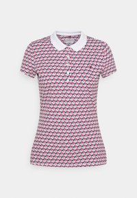 Short-sleeved polo shirt in white with a repeating geometric pattern in red and navy. Features a classic collar and fitted silhouette.