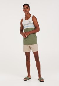 Green and gray tank top with horizontal stripes, beige shorts, and green slide sandals; simple, casual summer outfit.