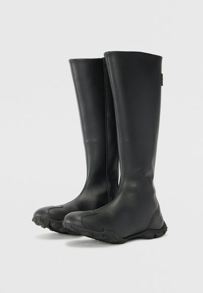 Black rubber knee-high boots with a smooth finish, rounded toes, textured soles, and minimalist design. Suitable for wet conditions.