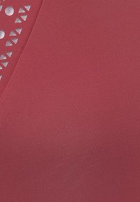 Karmesinrote Stretchstoff mit dreieckigen Ausschnitten und kreisförmigen Perforationen entlang des Ausschnitts; glatte Textur mit subtiler Glanz.