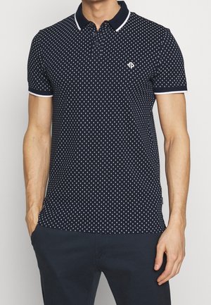 Polo navy avec un motif géométrique blanc, design col, et poignets côtelés. Il présente une patte de boutonnage à trois boutons et un logo sur la poitrine.