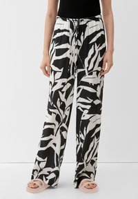 Pantalon à motifs noir et blanc, coupe ample, doté d'une taille à cordon de serrage. Le matériau semble léger avec une texture lisse.
