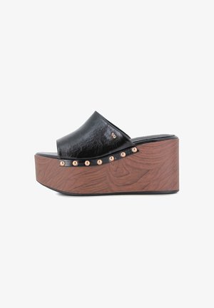 Sandalia negra de cuña con plataforma, puntera abierta, suela con textura de madera y detalles de tachuelas doradas a lo largo de la base de la tira superior.