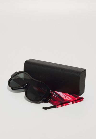 Occhiali da sole neri con un design unico, caratterizzati da una montatura spessa e lenti scure. Include una custodia nera e un panno per la pulizia con un motivo rosso.