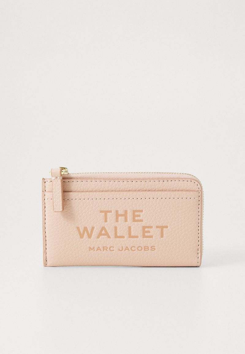 Rozā ādas maciņš ar paugurētu tekstūru, ar rāvējslēdzēja aizdari, iegravētu tekstu "THE WALLET" un zelta akcentu uz rāvējslēdzēja.
