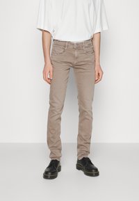 Beige slim-fit jeans i bomullsmix med framfickor och sömdetaljer. I kombination med svarta skor och en lös vit t-shirt.