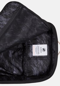 Borsa da viaggio nera con interno testurizzato, tasca con zip in rete e etichetta. Presenta una chiusura con zip e un design elegante per un'organizzazione ottimale.