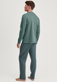 Lange mouwen, groene katoenen top gecombineerd met gestreepte, blauwe broek met geometrische ontwerpen. Casual pasvorm met een ontspannen silhouet.