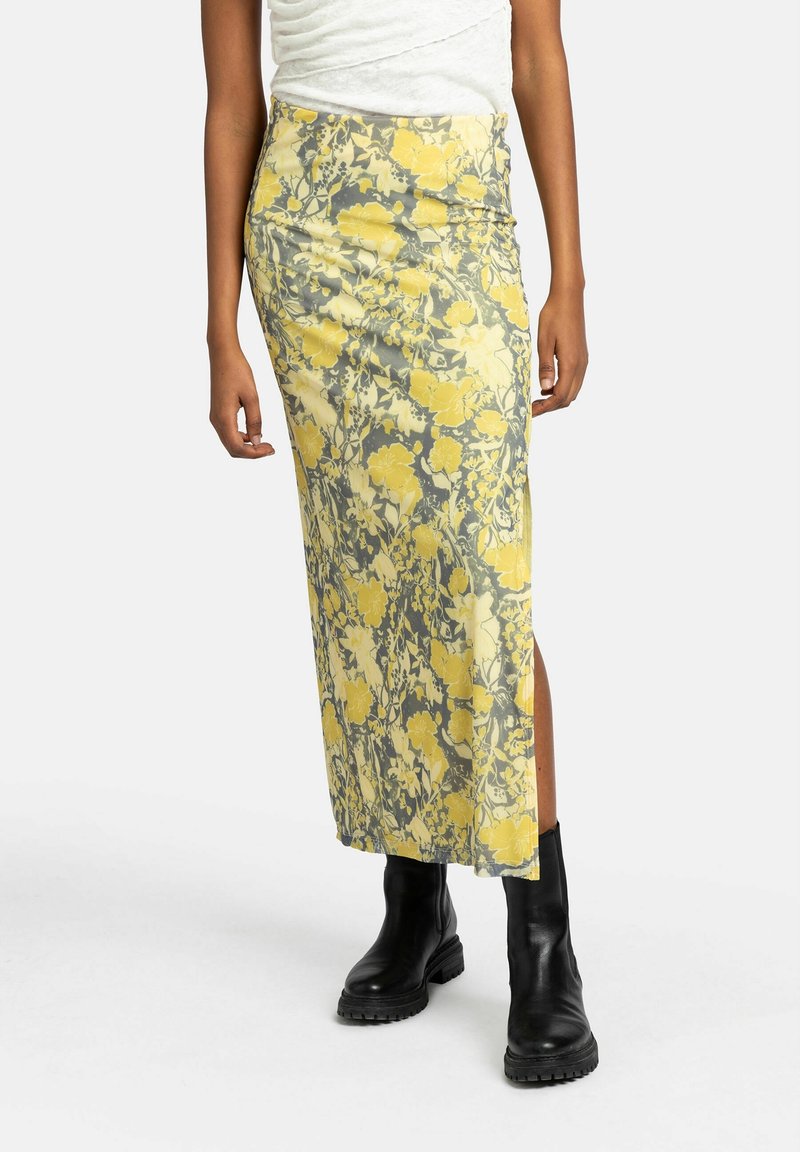 Gonna midi floreale nei toni giallo e grigio, caratterizzata da un design aderente, una spaccatura laterale e una texture liscia, abbinata a stivali neri alla caviglia.