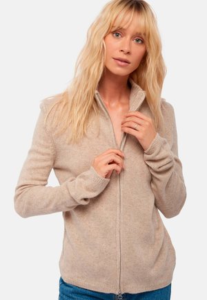 Beige zip-up sweater made of soft material, featuring a high collar, ribbed cuffs, and a relaxed fit. Zipper runs down the center front.