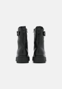 Bottines en cuir noir avec un design élégant, deux zips latéraux et une semelle en caoutchouc chunky avec une finition texturée.