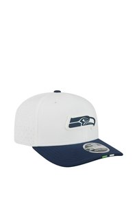 White and navy baseball cap with a navy bird logo on the front and a curved brim with a sticker on it.