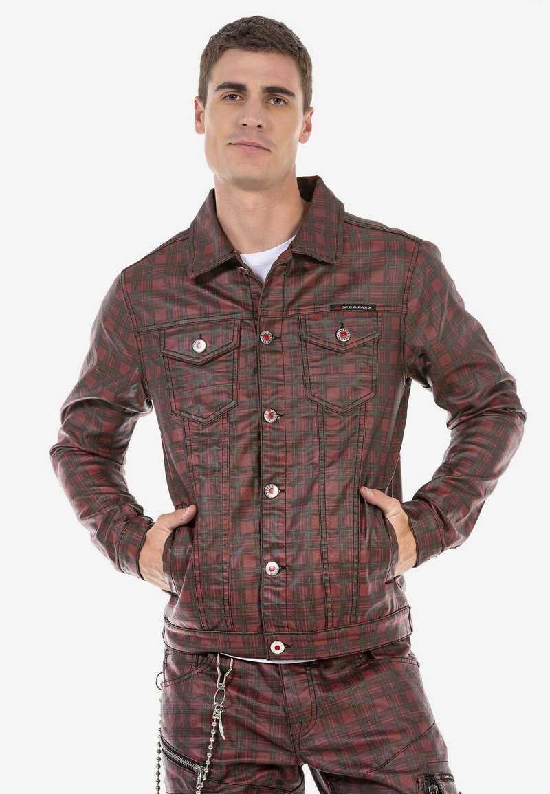 Rot-grüner Karodruck auf einer Jeansjacke mit zwei Brusttaschen, silbernen Akzenten und Knopfverschluss. Hat ein klassisches Kragen-Design.