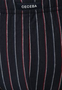 Navy gestreepte stof met witte en rode lijnen; bevat een "CECEBA" label. Materiaal lijkt zacht met een gestructureerde afwerking, op maat gemaakt ontwerp.