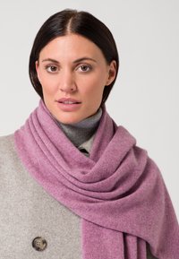 Sciarpa di lana viola chiaro drappeggiata attorno a un top grigio, con una texture morbida e un aspetto dolce e fluido.