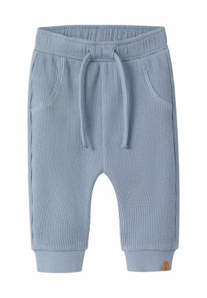 Lyseblå ribstrikkede babybukser med elastik i taljen, snøre, sidelommer og ribkant ved anklerne.