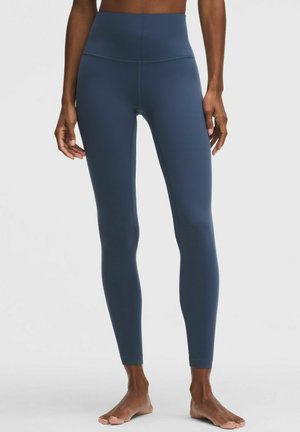 High-waisted, navy leggings made of smooth, stretchy fabric. Features a seamless design and tapered legs for a fitted silhouette.