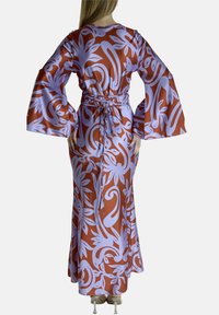 Vestido largo y fluido con mangas acampanadas, que presenta un fondo marrón y un patrón floral en lavanda. Confeccionado en tela suave y con una cintura ajustable.