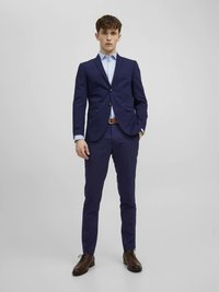 Completo blu navy con blazer monopetto con un bottone, pantaloni slim-fit abbinati, camicia azzurro chiaro e scarpe in pelle marrone. Tessuto liscio con vestibilità sartoriale.