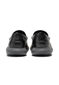 Svarta läderskor med en slät yta, som har en låg profil, grå gummisulor och en vävd accent detalj på baksidan.