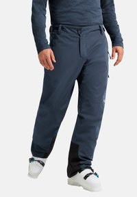 Waterdichte skibroek in donkerblauw. Kenmerken zijn onder meer ritszakken, een verstelbare taille en zwarte accenten op de onderbenen. Glad textuur.