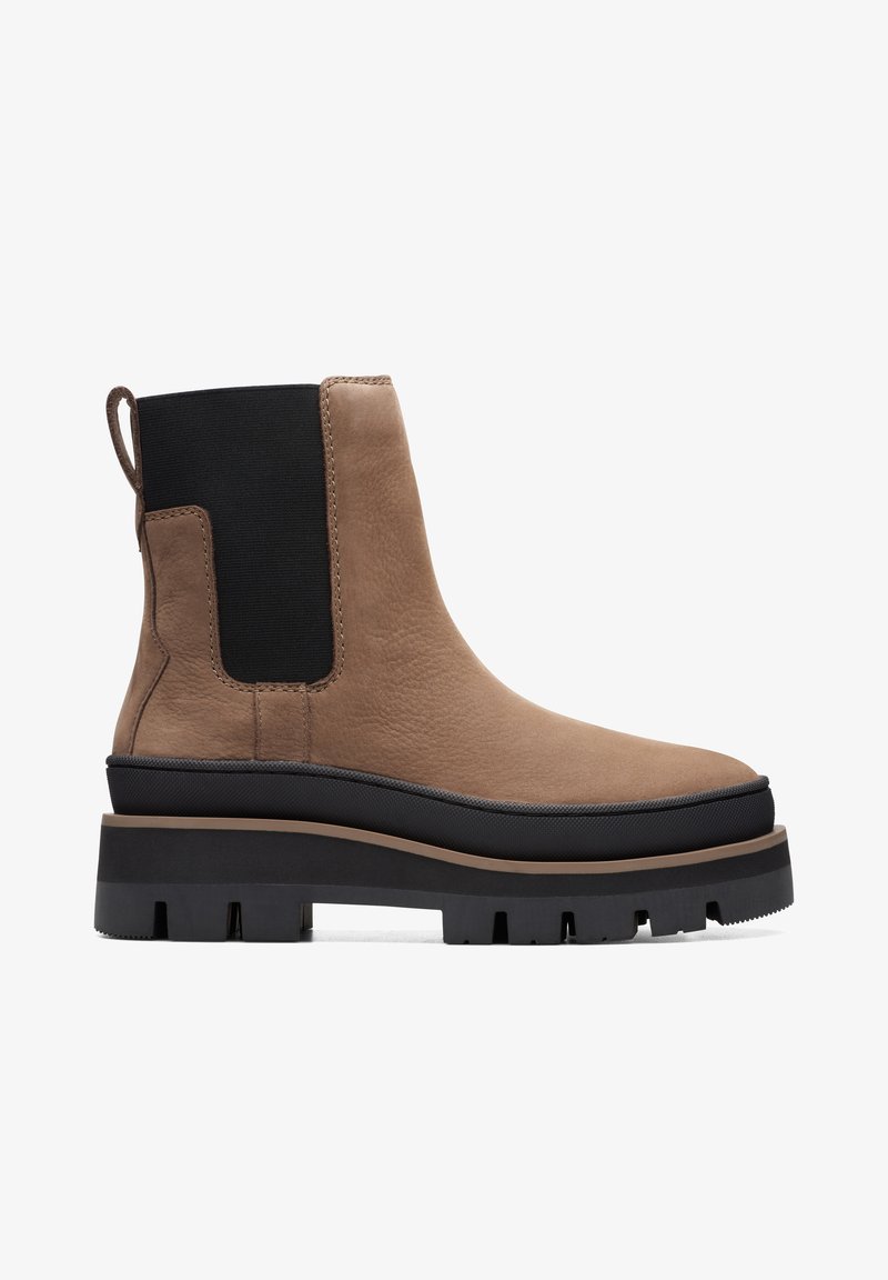 Bottine en cuir marron avec panneau latéral élastique noir, semelle épaisse noire à crampons et languette au talon sur fond blanc.