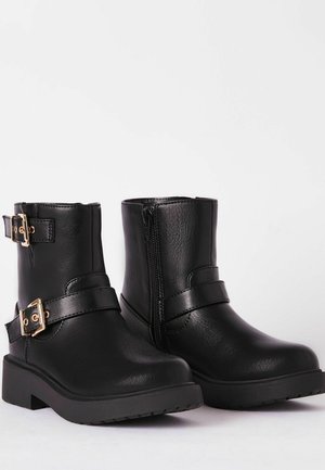 Bottines noires en cuir synthétique lisse, avec des accents de boucle dorée et une fermeture éclair sur le côté. Design de talon conique solide.