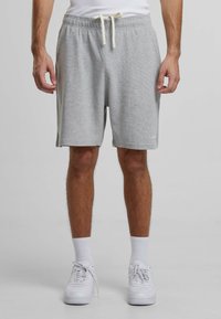 Pantaloni scurți de bumbac gri, cu un elastic la talie și șnur, buzunare laterale, textură moale și un tiv care se termină puțin deasupra genunchiului.