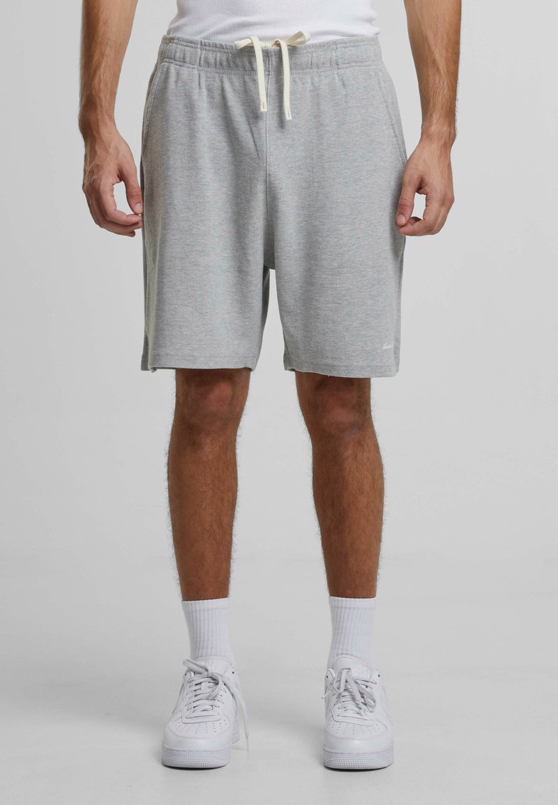 Pantaloni scurți de bumbac gri, cu un elastic la talie și șnur, buzunare laterale, textură moale și un tiv care se termină puțin deasupra genunchiului.