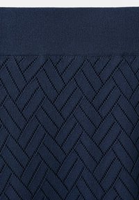 Tissu en maille bleu foncé avec un motif texturé en zigzag et diamants, bord solide côtelé en haut.