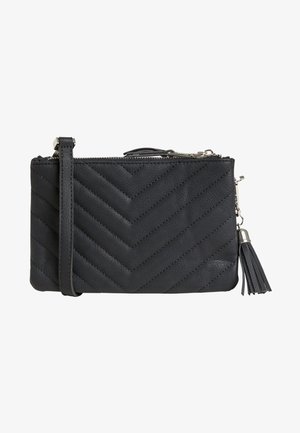 Pochette en cuir noir avec texture matelassée en chevrons, fermeture éclair, bandoulière amovible et un pompon en accent sur la fermeture éclair.