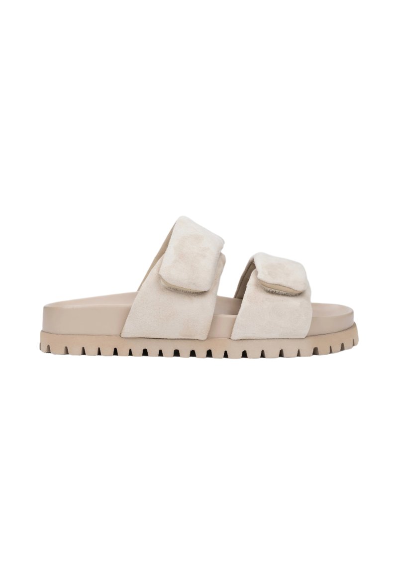 Beige suede slide sandals with two wide upper straps and a textured rubber sole featuring a ridged edge for grip.