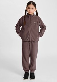 Fleece træningssæt i afdæmpet lilla, med jakke med lynlås og høj krave, elastiske manchetter samt matchende bukser med tætsiddende ankler.