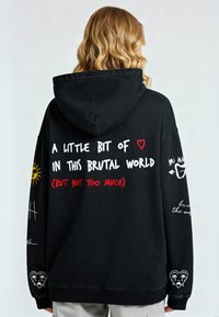 Juodas gobtuvas su baltais ir raudonais užrašais, saulės grafika ir širdies motyvais. Per didelis dydis su gumuotomis rankovėmis ir apačia.