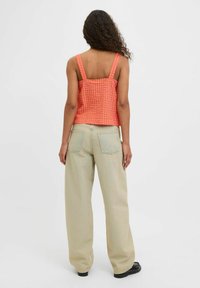 Top corto a quadretti rosa e arancione con spalline larghe, abbinato a pantaloni beige chiaro a gamba larga. Tessuto di cotone; texture morbida; design minimalista.