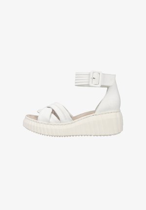White wedge sandals with crossed straps, a buckle ankle strap, and textured sole. The material appears smooth and leather-like.