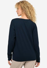 Granatowa koszula z długim rękawem o luźnym kroju, z okrągłym dekoltem i podwiniętymi rękawami. Wykonana z miękkiej, lekkiej tkaniny z widocznymi detalami szwu.