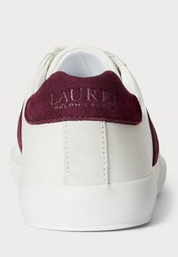 Biele tenisky s bordovým semišovým pätku. Obsahuje embosované logo "LAUREN RALPH LAUREN" a textúrovanú bielu gumovú podrážku.