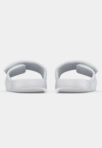 Sandales blanches au design minimaliste, dotées d'une semelle plate, de brides arrondies et d'accents rembourrés pour plus de confort. Texture lisse, sans motifs.