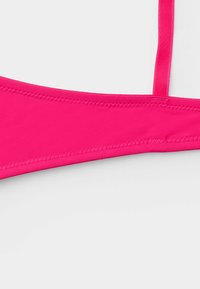 Růžový bikinový top s hladkou, pružnou texturou, tenkými ramínky a trojúhelníkovým tvarem. Obsahuje čisté prošívání podél okrajů.