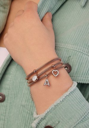 Drie metalen gaasarmbanden: één met een ronde bedel, één met de letter "A" en één met een hart, allemaal met sprankelende accenten.