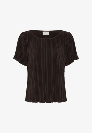 Femme portant un top court noir plissé à manches courtes et un pantalon large assorti, tenant un sac à main blanc à pampilles et portant des sandales noires à talons.