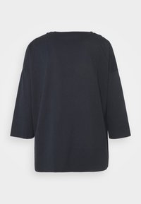 Schwarzes, übergroßes Shirt mit Dreiviertelärmel. Hergestellt aus weichem Stoff, verfügt es über einen runden Ausschnitt und einen geraden Schnitt am Saum.