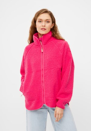 Fleece jack in helder roze met een hoge kraag en een volledige rits. Heeft raglanmouwen en een zachte, gestructureerde oppervlakte. Twee zijzakken.