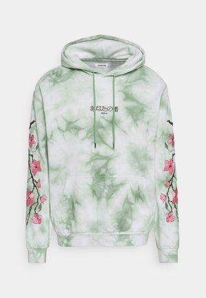 Hanorac verde cu tie-dye, dotat cu un buzunar frontal, șnur ajustabil și broderie florală roz pe mâneci. Design text pe piept.