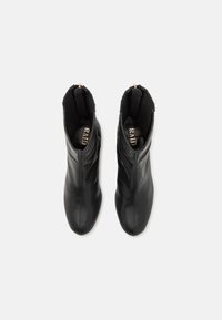 Botines negros de cuero liso con caña alta y detalles de punto acanalado. Cuentan con un zipper lateral para facilitar el uso.