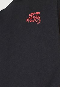 Black sweatshirt featuring a red graphic logo on the upper left side. The fabric has a soft texture with a classic crew neck design.